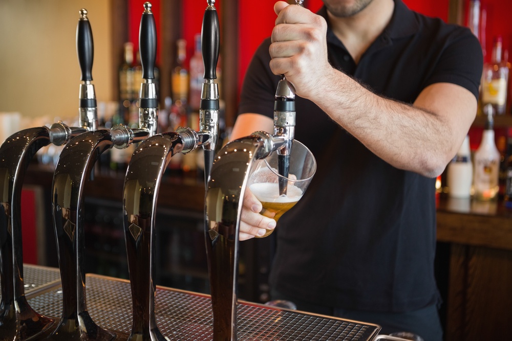 Barkeeper pulling a pint of beer behind the bar.jpeg